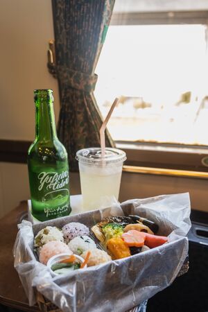 Yufuin,Oita,Kyushu,Japan - October 14, 2018 :Yufuin cider, special drink in Yufuin No Mori train, limited express train, route between Hakata station to Yufuin station, green bottle and bento sushi with sunlightのeditorial素材