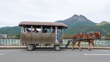 Yufuin,Oita,Kyushu,Japan - October 14, 2018 : The tourist on the horse carriage ride around Yufuin, river and Yufu mountain backgroundのeditorial素材