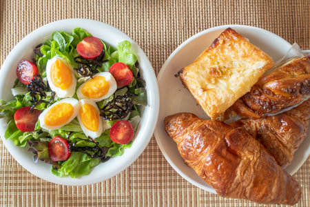 Green vegetable salad with leave,tomatoes,boiled eggs and microgreen on white plate on wooden table backgroundの写真素材