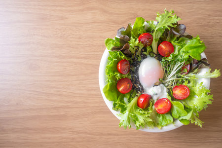 Green vegetable salad with leave,tomatoes,boiled eggs and microgreen on white plate on wooden table backgroundの写真素材