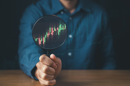 Businessman holding magnifier with financial graph growth for Investment Strategies and Financial Growth concept.の写真素材
