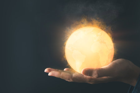 Businessman holding the hot earth with fire and smoke for saving climate change and global warming. net zero and sustainable living concept.の写真素材