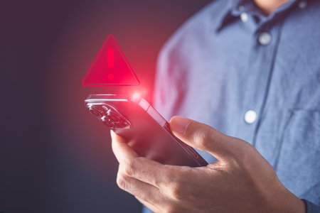 Businessman using mobile phone with red warning alert screen. System alert for virus,spam,scam and phishing. Cyber security, data security system concept.の写真素材