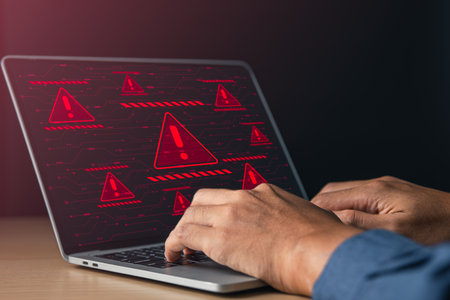 Businessman using laptop with red warning alert system hacked screen. System alert for virus,spam,scam and phishing. Cyber security, data security system concept.の写真素材