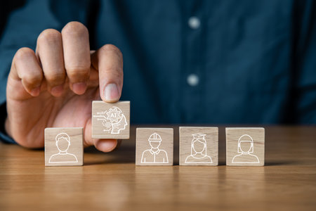man selecting wooden block of robot icon among blocks of human icons, symbolizing the choice of AI over human resources.AI artificial intelligence for futuristic and information technology conceptの写真素材