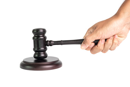 Hand holding wooden judge gavel isolated on white background for judgment and justice concept.の写真素材