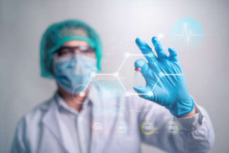 A doctor in blue gloves holding a vaccine bottle with transparent futuristic screen. Innovation Medicine and healthcare concept.の写真素材