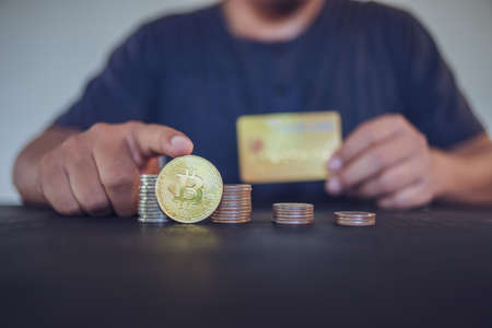 man holding a gold Bitcoin and credit card. Make money with bitcoin, digital currency money investment concept, blockchain transfer.の写真素材