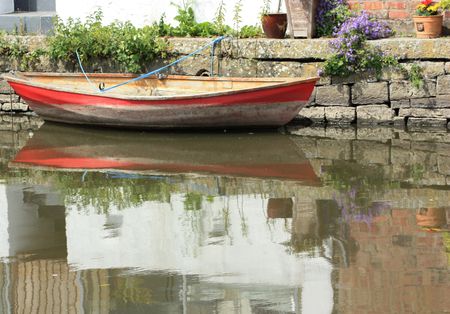 red and white boat tied up against a wall on a riverの写真素材