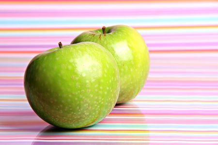  bright green apples sitting against a reflective stripy background looking ripe and ready to eatの写真素材