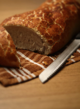 a loaf of bread cut open on a table with a knife next to it. images was shot at F1.8 for extreme...
