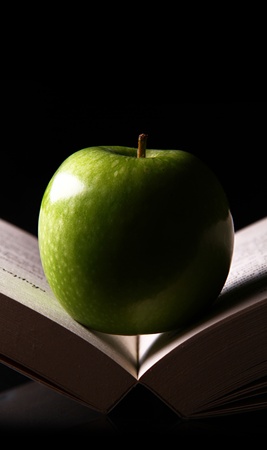 A green apple lies in the middle of an open book,の写真素材