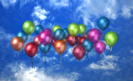 A large group of balloons floating in the bright blue sky with clouds の写真素材