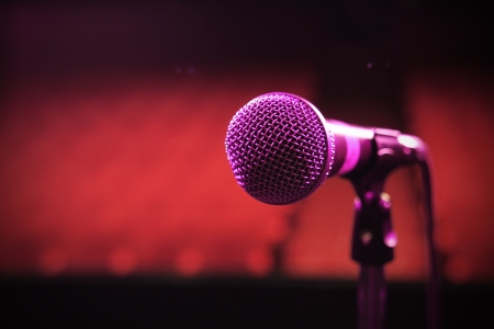a shot of a microphone on its own on a stage lit up by a red and blue lightの写真素材