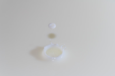 Splashing milk drop on a white milk backgroundの写真素材