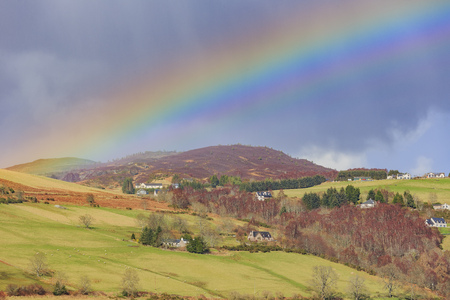 Beautiful rainbow with fields, houses at Highland, Scotlandの写真素材