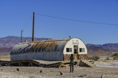 Special abandoned house with blue sky and woman below at Tecopa, Californiaのeditorial素材