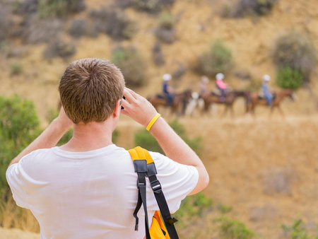 Los Angeles, JUL 20: Man taking photo of Horseback riding in Hollywood Hills trail on JUL 20,2014 at...