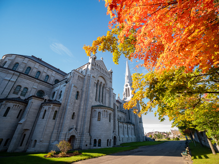 Exterior morning view of the Basilica of Sainte-Anne-de-Beaupre church with red maple tree at Quebec, Canadaの写真素材