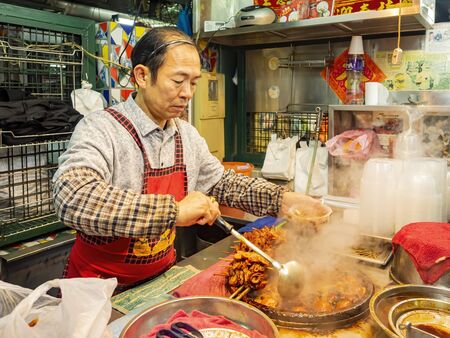 Macau, DEC 24: Man serving the traditional Pork knuckles and ginger stew on DEC 24, 2019 at Macau, Chinaのeditorial素材