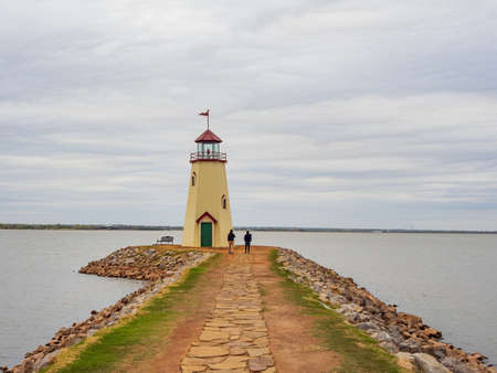 Overcast view of two women walking towards the lighthouse of Lake Hefner at Oklahomaの写真素材