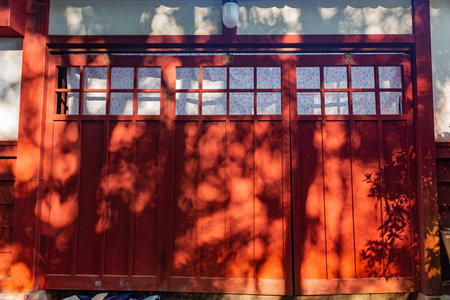 Sunny view of a red wooden house with tree shadow at Kyotoの写真素材