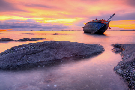 Twilight beached fishing boat capsized in Thailand.の写真素材