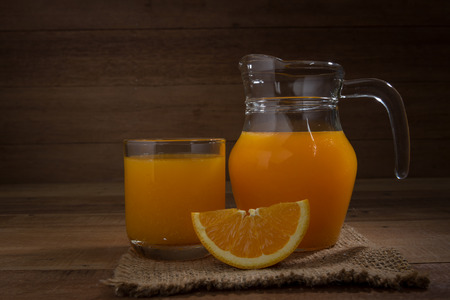 Orange juice in a glass and pitcher  on wooden backgroundの写真素材