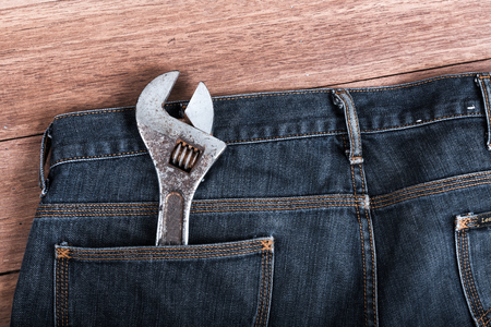 The wrench in the pocket of jeans On a wooden table backgroundの写真素材