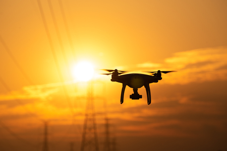 Drone surveying High voltage towers the sunset backgroundの写真素材