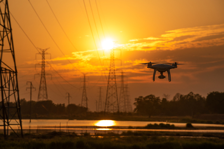 Drone surveying High voltage towers the sunset background