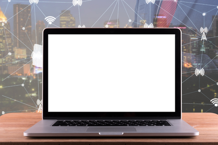 Laptop with blank screen on table. Double exposure. Business concept and cityscape and network connection concept,の写真素材