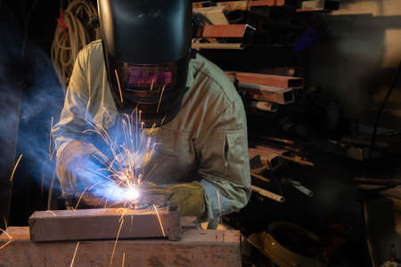 A welder is welding steel in an industrial factory. The welder wears protective clothing to work in the workplace.の写真素材