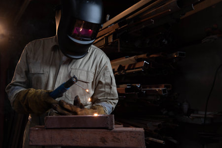 A welder is welding steel in an industrial factory. The welder wears protective clothing to work in the workplace.の写真素材