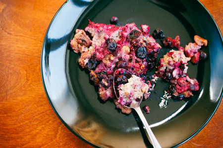 baked oatmeal with blackcurrant and walnut on black plate, tonedの写真素材