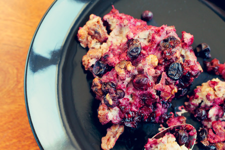 oatmeal, blackcurrant and walnut casserole on black plate, close-up, tonedの写真素材