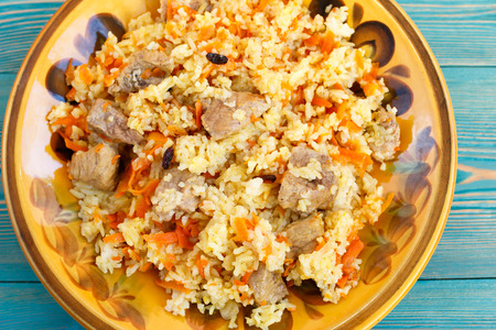 oriental pilaf, rice with meat and carrot on yellow plateの写真素材