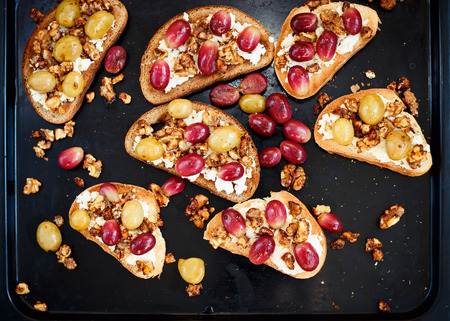 toasts with ricotta, baked grapes, walnut on blackの写真素材