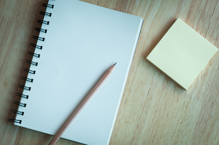 Notebook and pencil on wooden table with notepadの写真素材