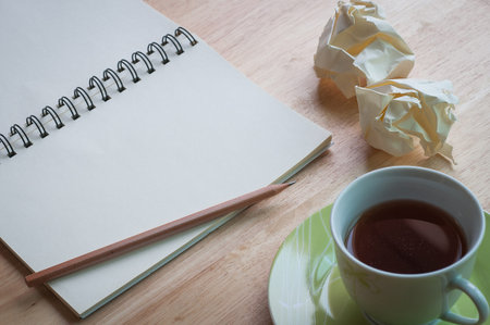 Working with blank notebook on wooden desk background with coffee cup and waste paper