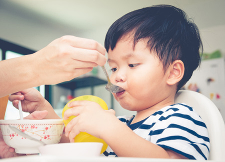 Asian toddler boy eating on high chairの写真素材