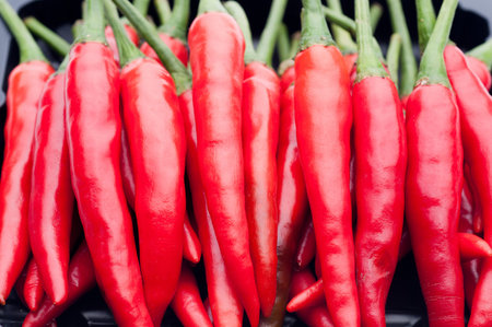 Heap of red hot chili pepper in black container.