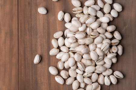 Roasted and salted pistachios in shell on wooden background.
