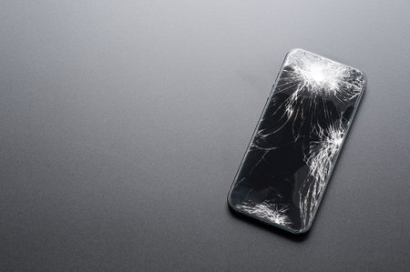 Smartphone with broken screen on dark background