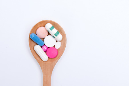 Capsules tablets on wooden spoon White backgroundの写真素材