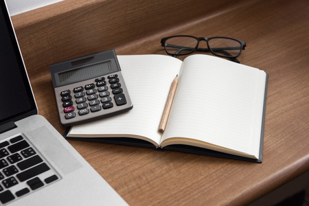 The notebook is spread out on a wooden desk.の写真素材