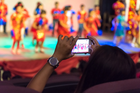 woman are using the mobile phone to take pictures of the stage.の写真素材