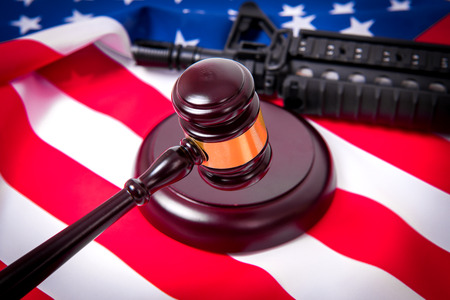 Gavel with gun on background of USA flagの写真素材