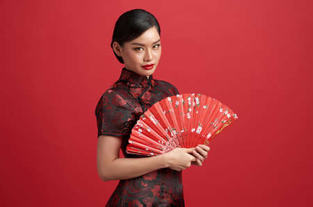 Asian chinese woman in traditional dress on red background. Chinese new year festival.の写真素材