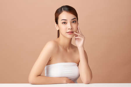 Beautiful young asian woman with clean fresh skin on beige background, Face care, Facial treatment, Cosmetology, beauty and spa, Asian women portraitの写真素材